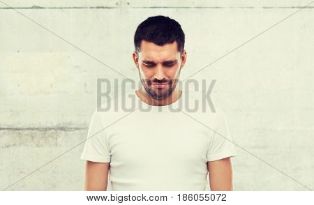emotion, sadness and people concept - unhappy young man over gray wall background