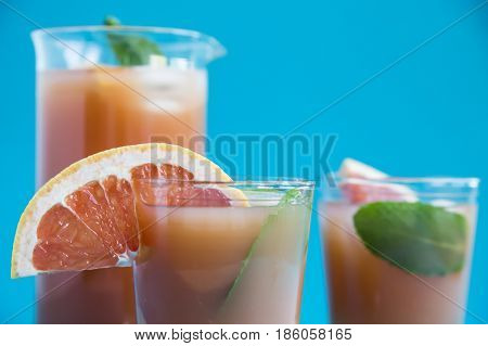 Grapefruit alcoholic cocktail with pieces of fruit, ice and mint