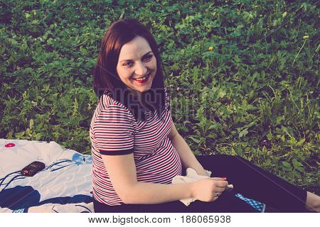 Happy young pregnant woman playing with baby sweater. slowmotion