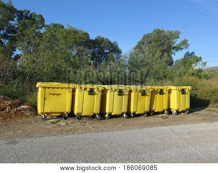 Collection of yellow recycling containers on rural road side