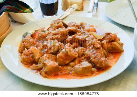 Plate of beef with tomato sauce and onions in a restaurant Cretan