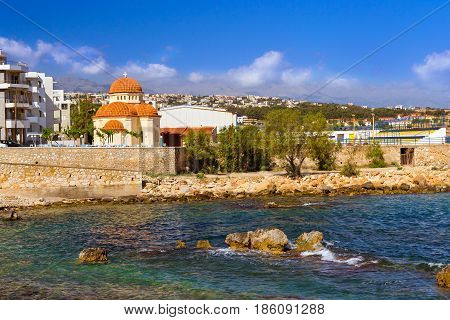 Eastern Orthodox Church of Holy Chapel Of Saint Nicholas. Place of worship on coast of Kolpos Almirou in Greek resort Rethymno. Promenade Leof. Emmanouil Kefalogianni is washed by Cretan sea. Greece