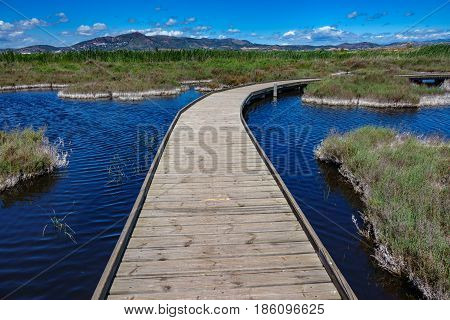 Wide angle view of curved wooden bridge across in lake