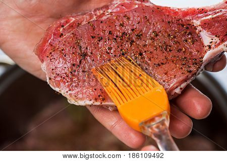 Close up of chefs hands spicing the meat. Casserole with raw meat on a white background.