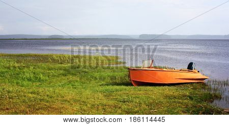 Orange boat at the lakeshore. Russian North. Tonde photo. Wide format. Sunny summer day. Kenozersky National Park Arkhangelsk region.