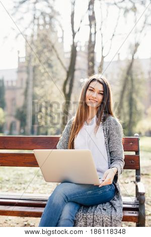 Portrait Of A Young Professional Woman Using A Laptop Computer While Sitting On A Bench In A Park, O