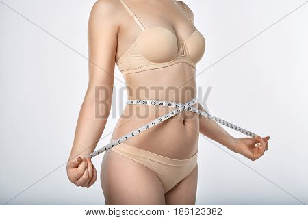 woman with meter at figure beige bra and lingerie isolated