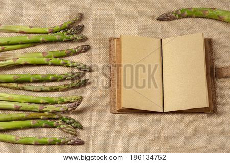 Asparges and Clear Notebook lying on a brown old sackcloth surface