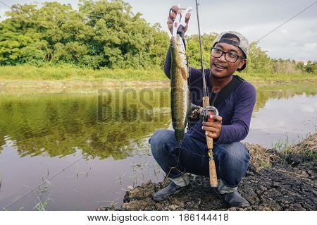 Labuan,Malaysia-May 7,2017:Fisherman holding a fresh striped snakehead fish caught by a fisherman in Labuan river,Malaysia.The snakeheads are members of the freshwater perciform fish family Channidae, native to parts of Africa and Asia.
