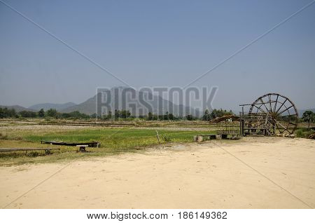 Thai Dam Cultural Village and big wooden turbine baler water wheel or wood noria water with landscape rice field mountain in Chiang Khan at Loei, Thailand