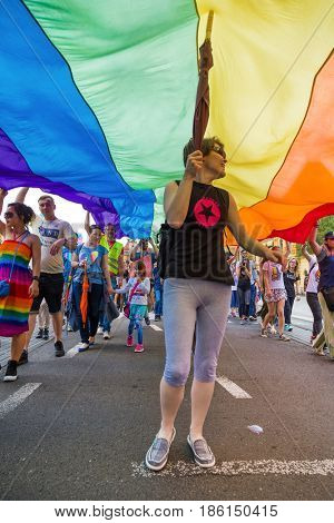ZAGREB, CROATIA - JUNE 11, 2016: 15th Zagreb pride. LGBTIQ activist under big rainbow flag.
