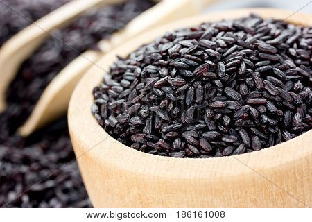 Unpolished black rice in a wooden bowl closeup