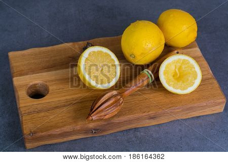 Ripe juicy yellow lemons witn juicer stick made from olive tree wood