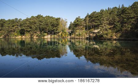 Beautiful Vibrant Landscape Image Of Old Clay Pit Quarry Lake With Unusual Colored Green Water