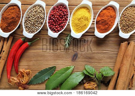 Spices in ceramic containers on wooden background. Food and cuisine ingradients.