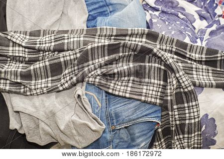 Lot of wrinkled clothes lying on sofa