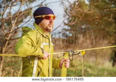 Close-up A man adjusts the slacklining of equipment before performing crazy slacklining tricks and walking on a slacklin in a park in the nature
