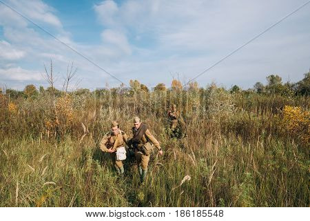 Dyatlovichi, Belarus - October 1, 2016: Reenactors Dressed As Russian Soviet Red Army Soldiers Of World War II Walking With With Maxim's Machine Gun Weapon In Autumn Meadow Forest