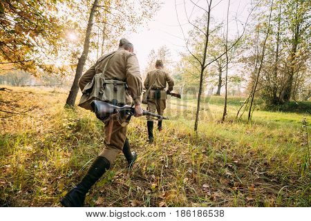 Two Re-enactors Dressed As Russian Soviet Red Army Soldiers Of World War II Hidden Running To Enemy Positions In Autumn Forest During Historical Reenactment.