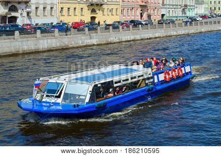 SAINT PETERSBURG RUSSIA - MAY 1 2017: Sightseeing boat goes along Fontanka River. Unidentified tourists are visiting sights during walk along rivers and canals of city