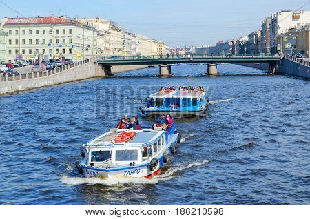 SAINT PETERSBURG RUSSIA - MAY 1 2017: Excursion boats on Fontanka River near Semyonovsky bridge. Unidentified tourists are visiting sights during walk along rivers and canals of city