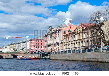 SAINT PETERSBURG RUSSIA - MAY 3 2017: Excursion ships on Fontanka River near Anichkov Bridge in St. Petersburg. Unknown tourists are going to see sights during walk along rivers and canals of city