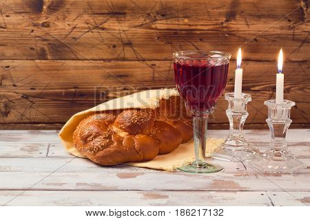 Shabbat concept with wine glass and challah bread on wooden table