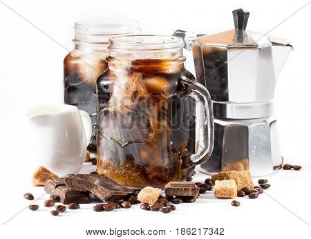 iced coffee in a large mug. coffee beans, pieces of chocolate and coffee pot on a white background