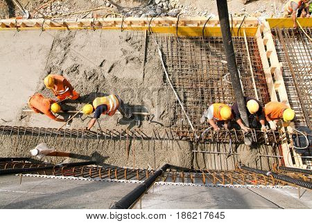 Street Workers Pouring Cement With A Pump Into A Highway Construction