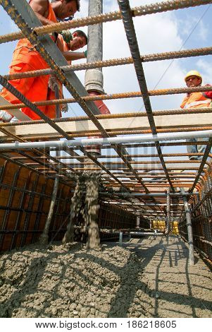 Street Workers Pouring Cement With A Pump Into A Highway Construction