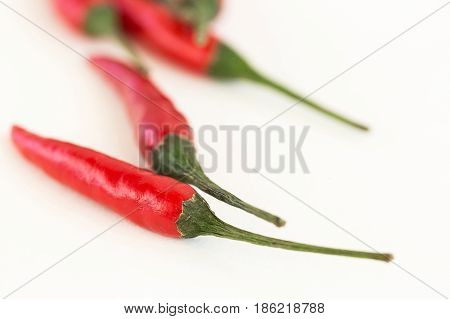 red hot chili peppers, popular spices concept - close-up on three delicious juicy clean pod of red hot chili peppers laying on white background, selective focus