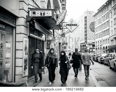 STRASBOURG FRANCE - MAY 7 2017: Three muslims girls walking on trottoir under Loto and press signage in French city of Strasbourg