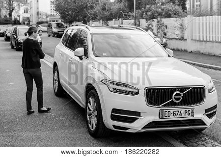PARIS FRANCE - APR 2 2017: French woman aproaching her luxury white Volvo XC90 the luxury crossover SUV manufactured and marketed by Volvo Cars