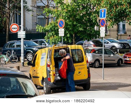 STRASBOURG FRANCE - APR 12 2017: Yellow van of La Poste - French National Postal service with postal driver worker searching gor the right parcel to deliver near French building