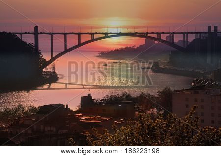 The Arrabida bridge over the Douro River in the rays of the setting sun. Porto Portugal