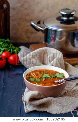 Georgian soup kharcho with cilantro and vegetables. The national Georgian dish is served with fresh lavash. Soup kharcho with vegetables and cilantro on a wooden table.