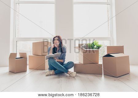 Pretty Minded Smiling Woman In Casual Clothes Sitting On The Floor Near Boxes With Stuff With Notepa