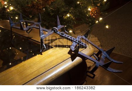 Rusty old crampons on a table with a Christmas tree behind