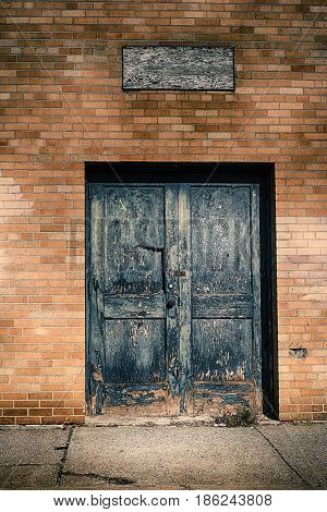 A blue broken textured door on yellow bricks.