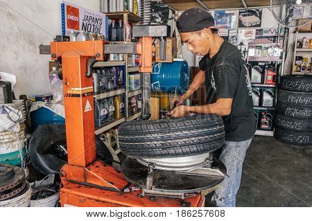 Labuan,Malaysia-May 9,2017:Car tire service mechanic changing car wheel before makes computer wheel balancing on special equipment machine tool in auto repair service in Labuan,Malaysia.