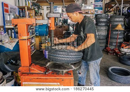 Labuan,Malaysia-May 9,2017:Car tire service mechanic changing car wheel before makes computer wheel balancing on special equipment machine tool in auto repair service in Labuan,Malaysia.