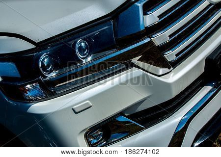 Fragment of the front of the car with a headlight and radiator grille with traces of dirt