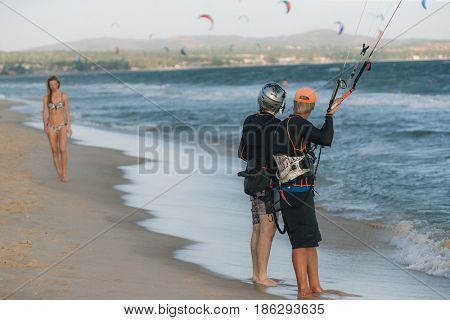 A kite surfer looking at woman on the beach
