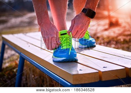 Athlete during training tying shoelaces on sneakers summer.