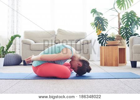 Side view shot of gorgeous female practicing seated bound lotus posture