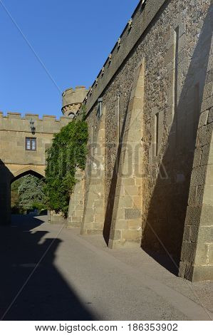 Vintage old-fashioned castle with turret, sunny morning. Vorontsov palace, Alupka, Crimea. Blue sky, mountain landscape. Scottish Baronial, Mughal architecture, Gothic Revival architecture styles.