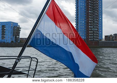 Flag of Netherlands waving on stern of tour boat. On ship in Amsterdam. Travel to Europe. Boat trip on the canals of Netherlands. Patriotic symbol banner. Dutch national official flag flying in wind
