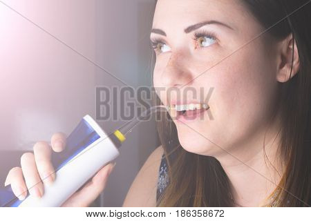 A woman using an oral irrigator in bathroom.