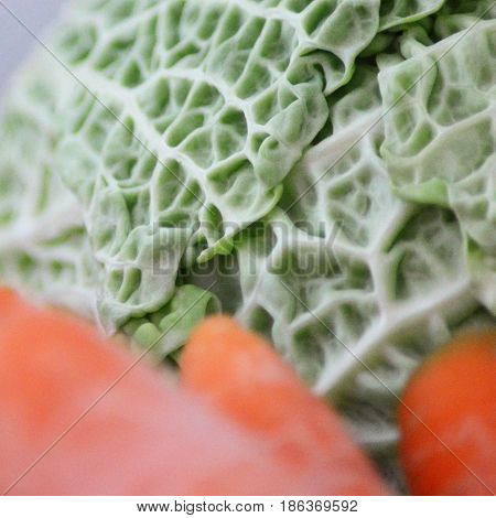 Fresh cabbage with blurred carrots in foreground