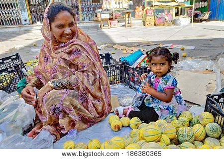 Bandar Abbas Hormozgan Province Iran - 16 april 2017: A street vendor melons smiles looking at her little daughter sitting on the sidewalk near her only for editorial use.